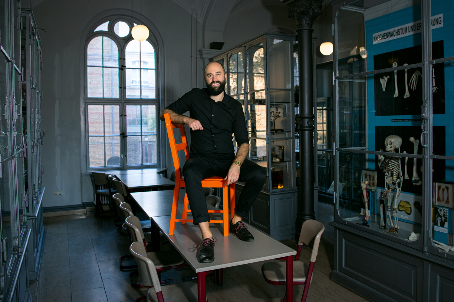Darren W. Wagner sitzt auf einem Stuhl auf einem Tisch in der Medizinhistorischen Sammlung der Charite